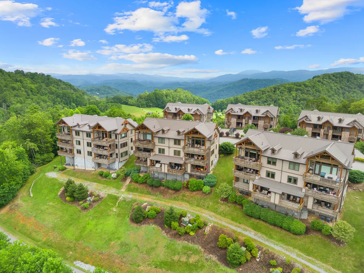 This image presents a tranquil exterior scene with modern buildings set against a majestic mountain backdrop. The well-maintained landscaping includes lush greenery and open spaces, evoking the natural beauty and adventure opportunities of the area.
