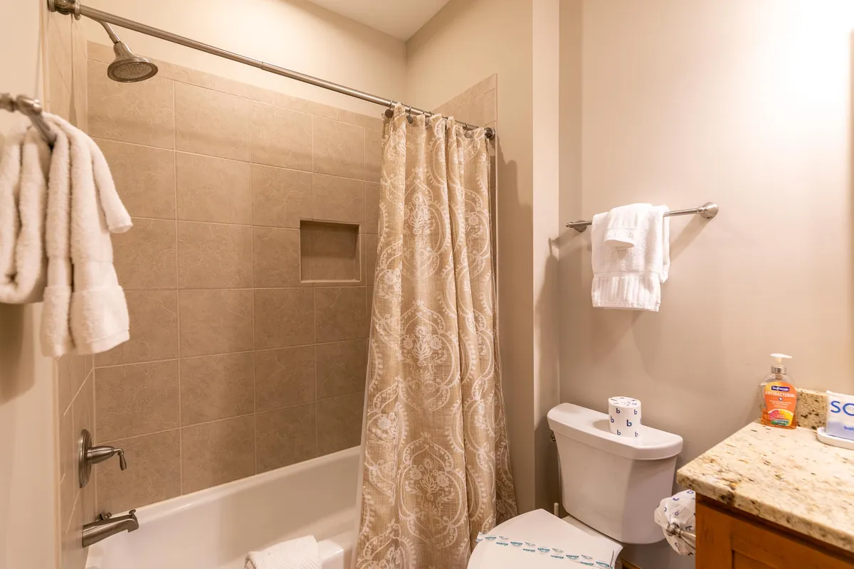 A bright, clean bathroom featuring a spacious bathtub, shower, vanity, and toilet. The area feels refreshing, ideal for unwinding after outdoor adventures like skiing or hiking.