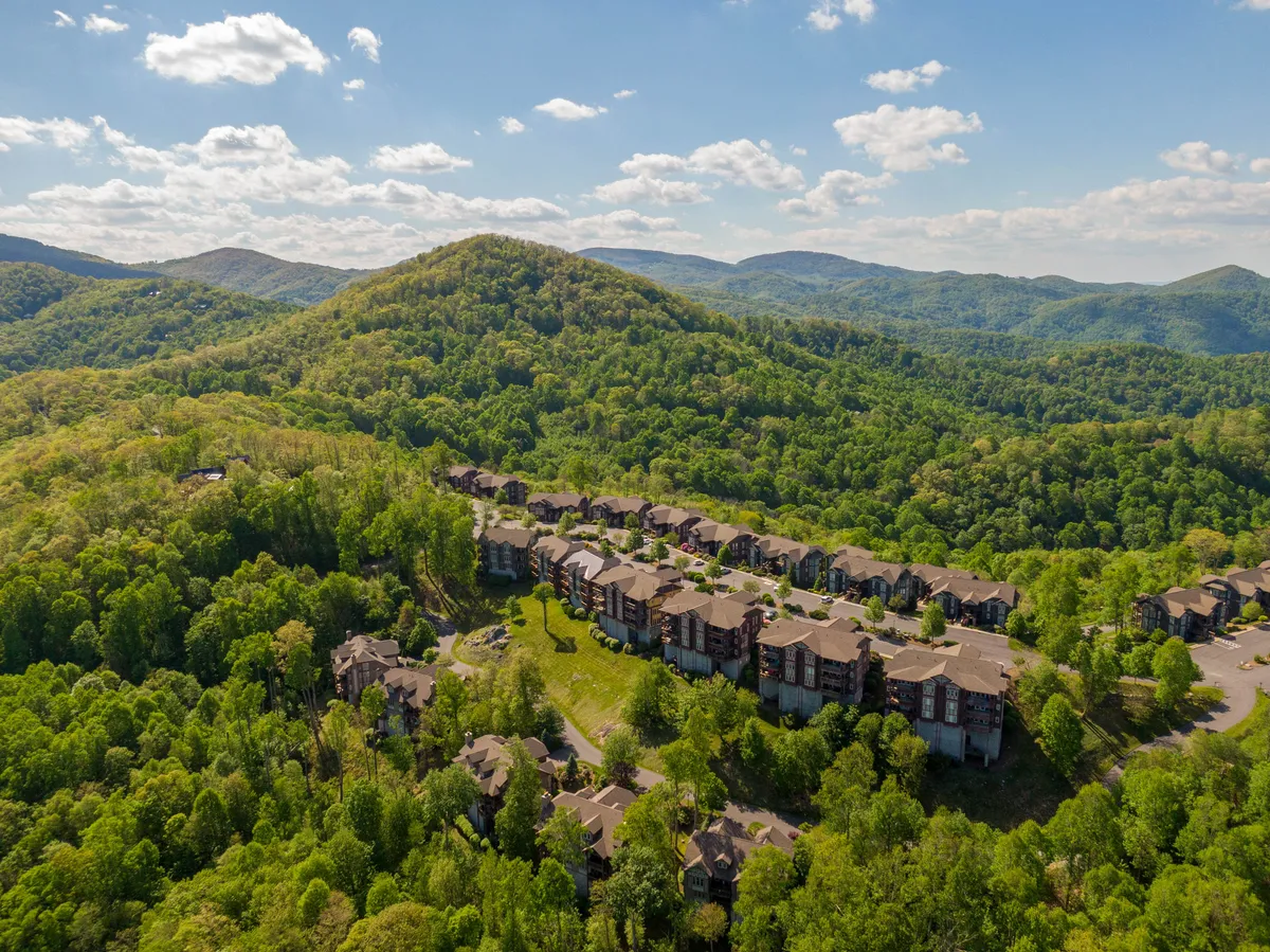This exterior image captures panoramic mountain views at sunset, with residential buildings nestled among greenery. The peaceful atmosphere suggests both relaxation and a scenic setting ideal for morning coffee on the deck, as well as outdoor gatherings.