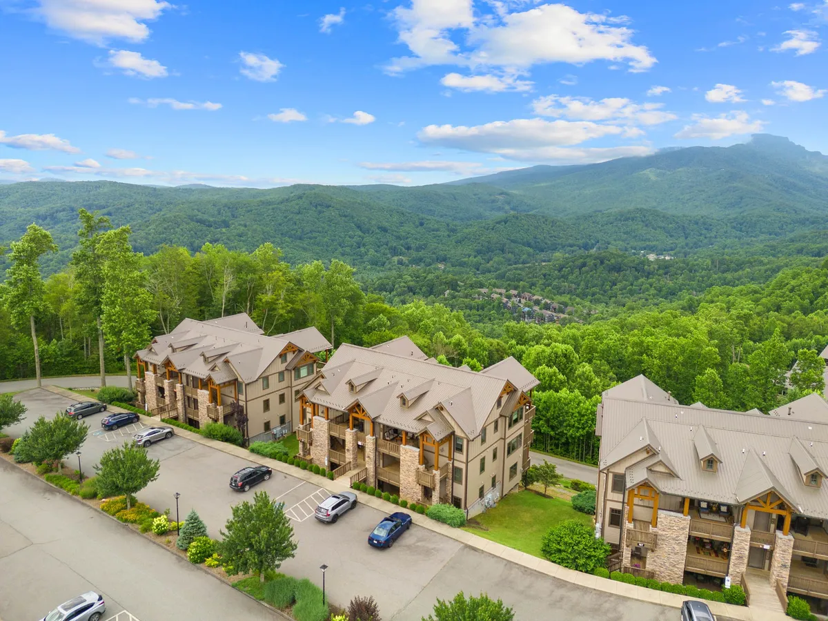 This image presents a multi-story building nestled among lush greenery, with a stunning mountain backdrop. The scene captures the serene atmosphere of the surroundings, with the building suggesting the upscale resort environment and the landscape emphasizing the connection to nature. The soft lighting hints at either sunrise or sunset, enhancing the sense of tranquility.