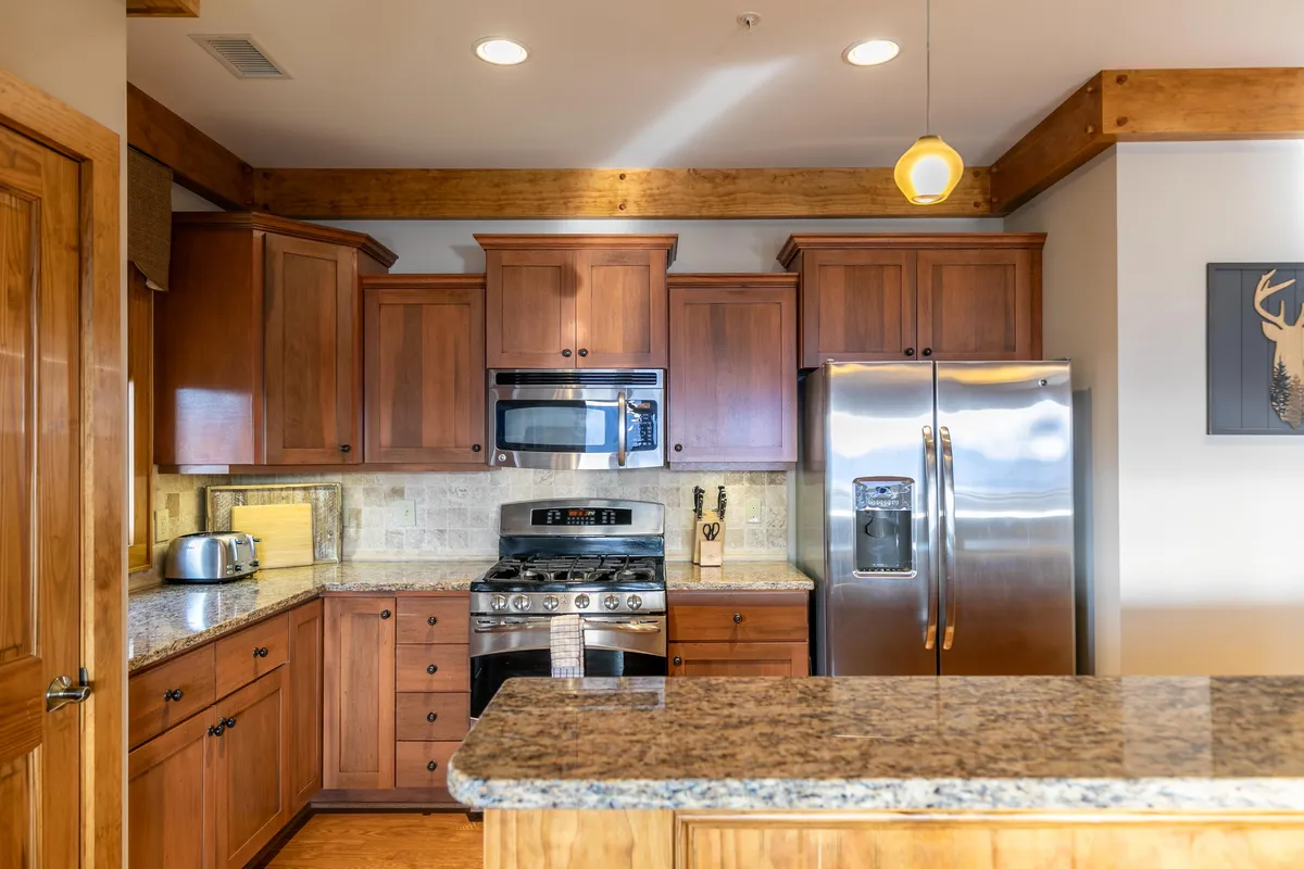 A kitchen area with granite countertops, stainless steel appliances, and wooden cabinetry. The space is both functional and cozy, perfect for preparing meals or settling in quickly after arrival.