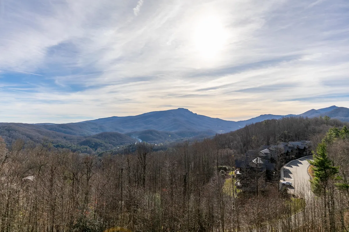 A sweeping view of the surrounding mountains and valleys, bathed in sunlight and dotted with trails. The scene invites exploration, relaxation, and outdoor adventure in the natural beauty that defines the community.